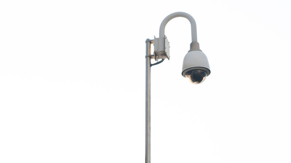 video surveillance camera on a pole against a white sky