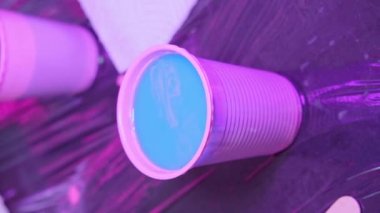 Dövmeci kız, pembe boyayı iğnelerden temizlemek için dövme makinesini mavi suya batırıyor.