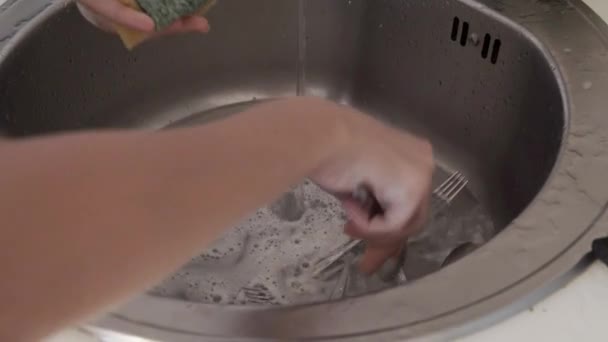 一名妇女用黄色海绵用洗涤剂在金属水池中洗大勺的特写镜头 — 图库视频影像