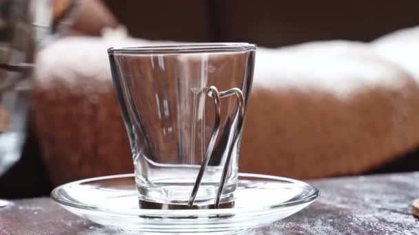 銀色の金属製ティーポットからグラスマグカップにハーブティーを注ぐというクローズアップ 暖かい冬の寒さでお茶 — ストック動画