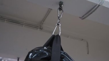 close-up of a metal carabiner attachment of a punching bag to the ceiling. A punching bag with black sand is attached to the ceiling. Sports equipment for martial arts