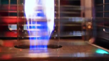 Metal ızgaradaki gaz yakıcısından çıkan güçlü bir ateşin yakın çekimi. Hortumdan ateşli bir jet geliyor. Gaz ocağındaki yangın..