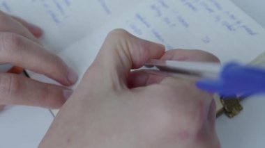 Toplantıda bir not defterine bilgi yazan bir kızın yakın çekimi. Derste not alıyorum. Kişisel günlük.