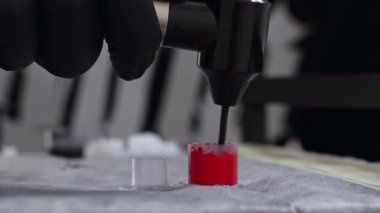 Yakın plan dövme sanatçısı birkaç dövme mürekkebini plastik bir şapkaya özel bir karıştırıcı ile karıştırıyor. Yüksek kalite 4k görüntü