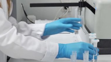 Laboratuvarda deney tüpleriyle çalışan tıbbi önlüklü ve eldivenli bir bilim adamının yakın çekimi. Yüksek kalite 4k görüntü