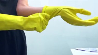 Temizlik için sarı lastik eldiven takan bir kızın yakın çekimi. Kız daireyi temizliyor. Yüksek kaliteli FullHD görüntüler