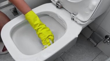 Eldivenli bir kadının tuvalete deterjan sürerken yakın çekimi. Tuvaleti temizliyorum. Yüksek kaliteli FullHD görüntüler