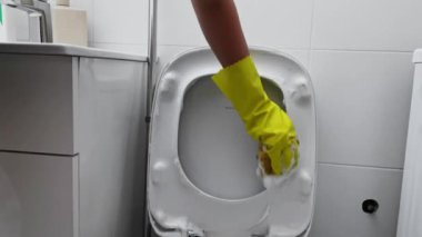 Eldivenli bir kadının tuvalete deterjan sürerken yakın çekimi. Tuvaleti temizliyorum. Yüksek kaliteli FullHD görüntüler
