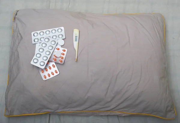 一包药丸和一个测量温度的电子温度计放在一个灰色枕头上 工作室Voto 顶层视图 — 图库照片