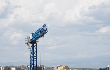 İnşaat vinci, gökyüzünün arka planında, bulutlarda ve diğer birçok gökdelende çalışırken. Yeni bir yerleşim alanının inşaatı.