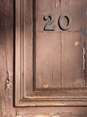 Kapının ahşap kaplamalı kahverengi yüzeyi metalik numaralar ve farklı ahşap dokulara sahip eski fotoğraflarda bulunan diğer ahşap mimari elementler. Yüksek kaliteli dikey fotoğraf .