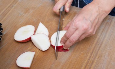 Ev yapımı ev yapımı lezzetli elmalı turta yapma süreci. Çiftlik evindeki ahşap el işi kumaş masasında hazırlanırken yakın plan eller görüntüsü. Tablonun yapılandırılmış kırsal yüzeyi.