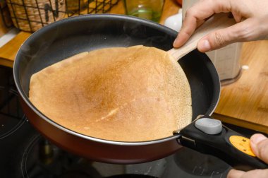Bir çiftlik evinin ev mutfağında kadınların elleri pişmiş krepleri tavadan çıkardığında lezzetli el yapımı altın krep yapma süreci. Tavada sıcak krep.