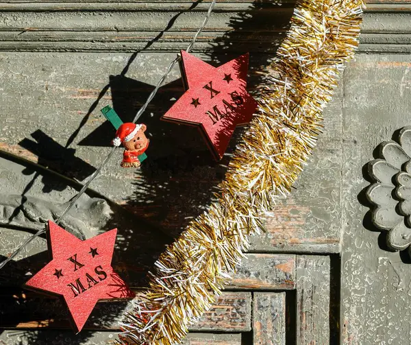 Tahta elektrik çelengi şeklinde Noel süslemeleri ve güneşte şöminenin önünde asılı sarı süslemeler..