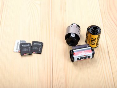 Bansko, Bulgaristan. 12.20.2021. Üç modern Sandisk mikro SD ve Samsung hafıza kartları dijital bir kamera için bir ahşap masa üzerine istiflenmiştir kamera için üç eski 35 mm film.