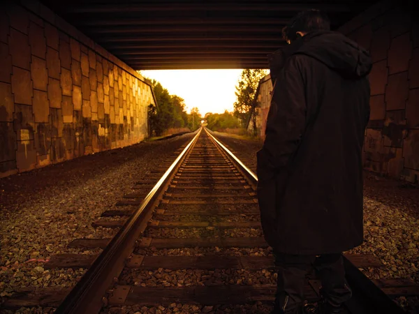 stock image man standing on railroad tracks in a tunnel during golden hour