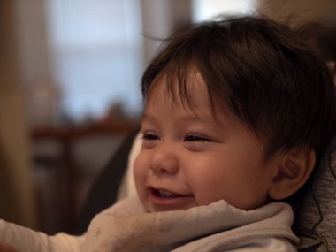 Yarı Asyalı yarı Asyalı bir erkek bebek gülümsüyor ve gülüyor.