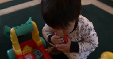 Koyu saçlı bebek evde yapı taşlarıyla oynuyor.