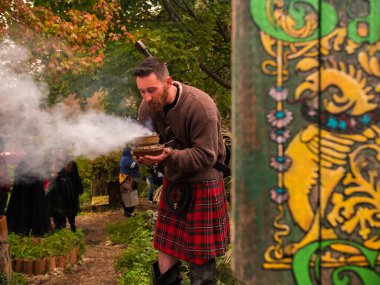 Festival sırasında dışarıda tütsü üfleyen İskoç bir adam.