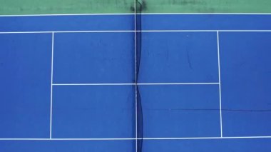 drone video of an empty blue and green tennis court in a residential area