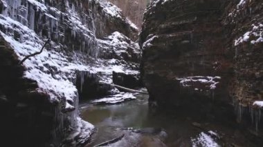 drone flying above a river flowing through a canyon during winter time
