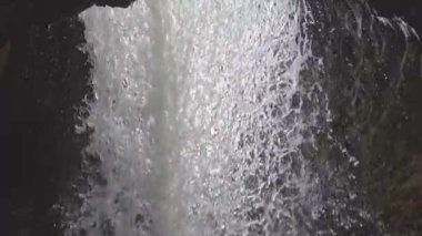 standing behind a waterfall in slow motion, underneath a waterfall