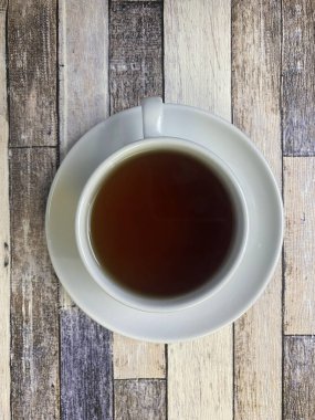 Eski ahşap arka planda, beyaz bir fincanda, düz bir fincan çay..