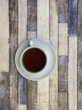 Eski ahşap arka planda, beyaz bir fincanda, düz bir fincan çay..