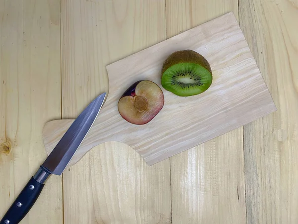 Kivi meyveleri ve ahşap bir tahta üzerinde erik parçaları. Kivi meyvesi parçaları, erik parçaları ve bıçak kavramı..