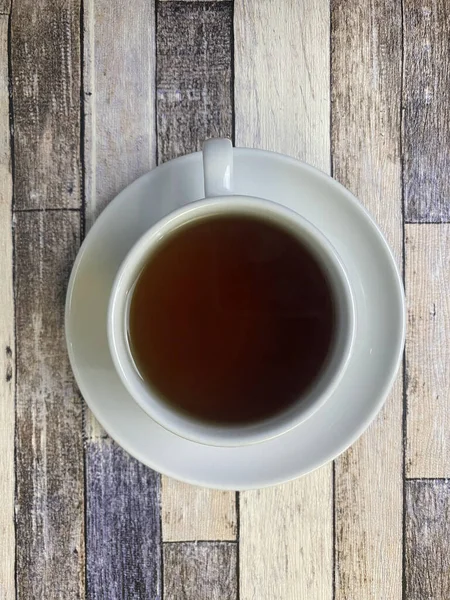 Eski ahşap arka planda, beyaz bir fincanda, düz bir fincan çay..
