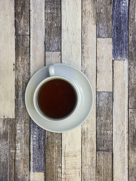 Eski ahşap arka planda, beyaz bir fincanda, düz bir fincan çay..