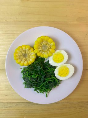 Tabakta haşlanmış mısır, haşlanmış ıspanak ve haşlanmış yumurta servis edilir. Diyet yemek ve sağlıklı yemek..