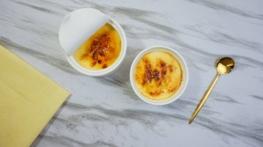 Masanın üzerinde beyaz kâse içinde ev yapımı kremalı brulee.