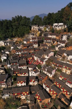Sonbaharda Çin 'in pitoresk bir köyünde, hasat mahsulleriyle süslenmiş çatılar geleneksel mimarinin arka planına karşı canlı bir sahne oluşturur..