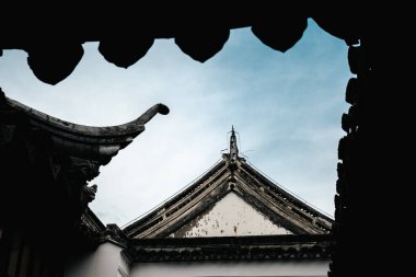 Geleneksel bir Çin tapınağının karmaşık çatı detaylarını yakalayan mimari yapı, zarif dekorasyonlar ve tarihsel tasarım elementlerini gökyüzüne karşı sergiliyor..