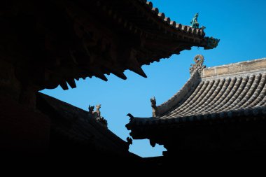 Parlak mavi gökyüzüne vurgulanan geleneksel bir Çin tapınağının karmaşık dizayn edilmiş çatıları süslemeleri gözler önüne seriyor..