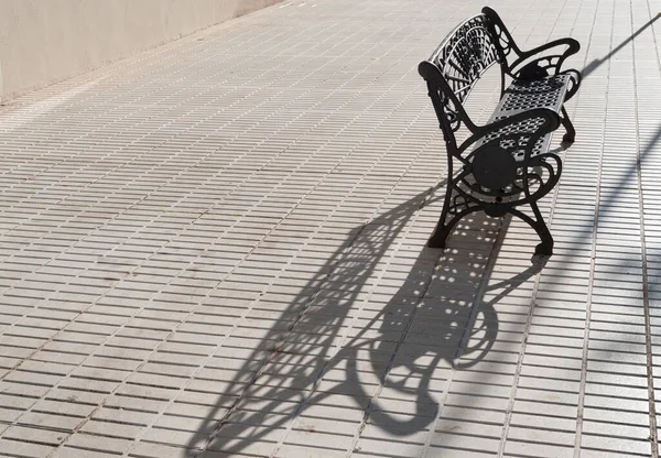 街上日落时的黑铁长椅 — 图库照片