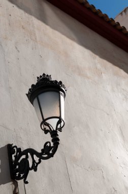 Güneşli bir duvarda antik bir sokak lambası