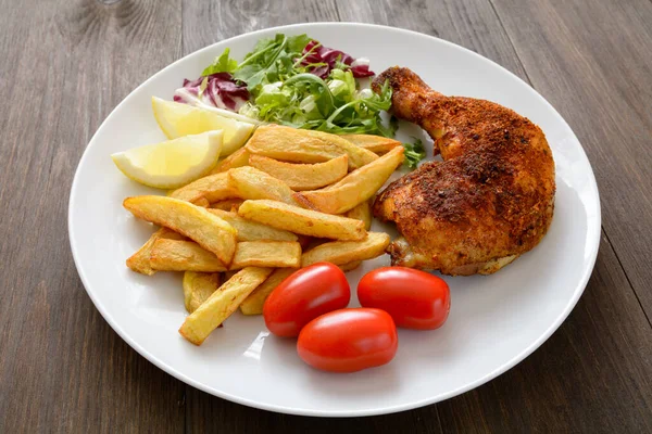 baked chicken leg with fries, salad and tomato