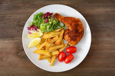 Kızarmış tavuk budu, salata ve domates.