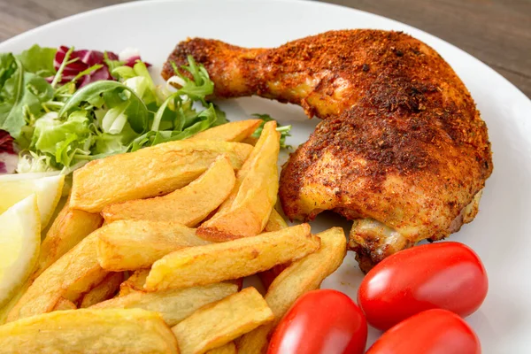chicken leg baked with fries, salad and tomato