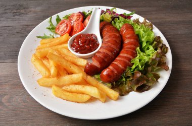 Kızarmış sosis, patates kızartması, marul ve domates.