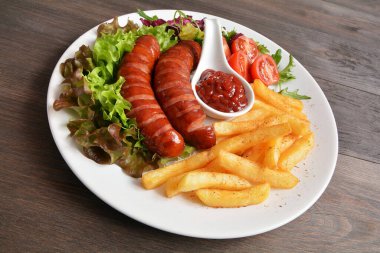 Kızarmış sosis, patates kızartması, marul ve domates.