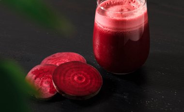 Koyu arkaplanda bir bardakta taze pancar suyu