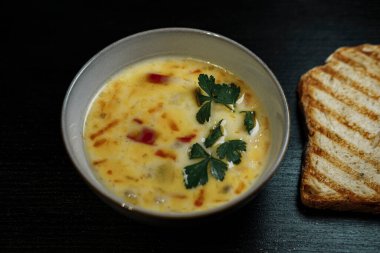Koyu arkaplanda kremalı sebze çorbası, gül tostlu ekmek