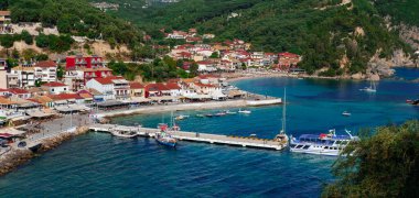 Parga kasabası, Yunanistan: 01 Haziran 2023: Deniz hattı, oteller, sahil kafeleri, feribot ve demirleme yerleri üzerindeki küçük renkli Yunan köyü veya kasaba manzarası