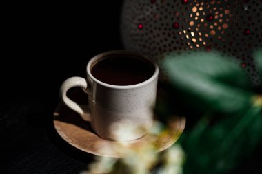 Türk kahvesi, geleneksel sedir içeceği, sıcak içecekler, mum ışığı ve koyu arkaplanda bitki ile süslenmiş.