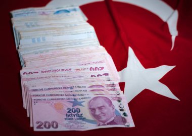 Türkiye 05 Temmuz 2023: Ulusal kırmızı bayrak üzerinde Türk lirası, kağıt para yığını, 200 ve 100 nominal değer banknotları