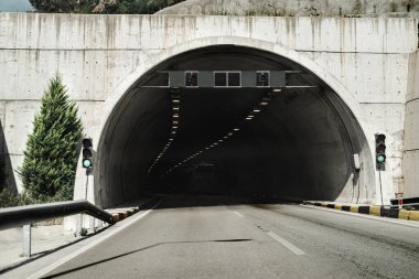 Dağ yolunda tünel girişi, yeşil trafik ışığı.