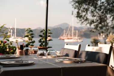Sahil kenarındaki restoranda servis masası, beyaz ve mavi renkler, gün batımı saati, Seaview 'da akşam yemeği.